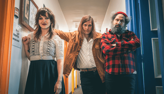 A trio of in a hallway looking at the camera