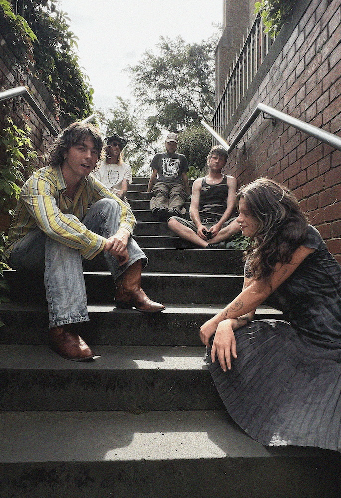 A band standing in a suburban backyard with a lemon tree in the background
